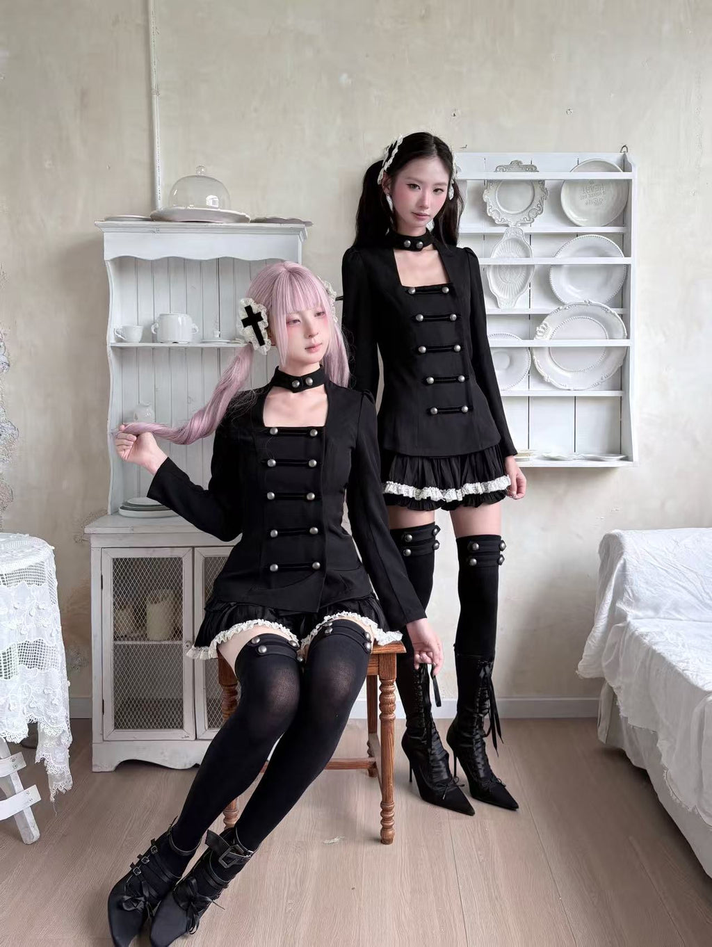 Two models wearing coordinated black gothic outfits